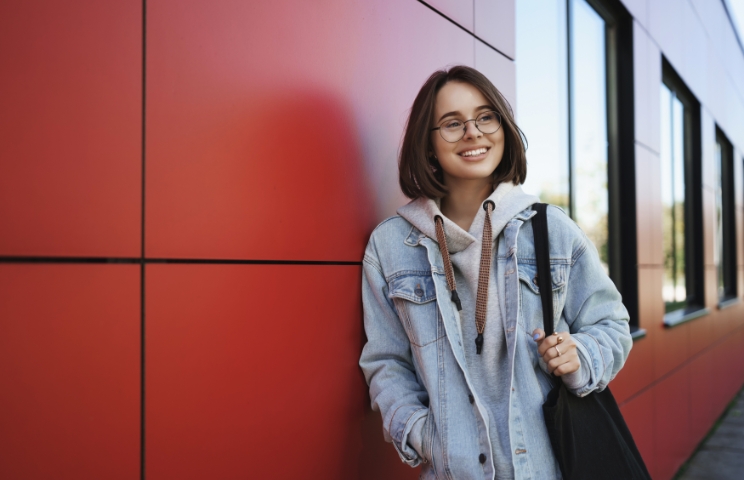 Young Generation Lifestyle Education Concept Outdoor Portrait Happy Girl Her Way Home After Classes Looking Sideways Dreamy Happy Smiling Holding Tote Bag Lean Red Building